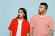 Young shocked surprised astonished couple two friends family Indian man woman wearing red casual clothes t-shirts look aside on area together isolated on pastel plain light blue cyan color background.