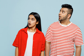 Wall Mural - Young shocked surprised astonished couple two friends family Indian man woman wearing red casual clothes t-shirts look aside on area together isolated on pastel plain light blue cyan color background.