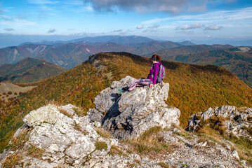 Wall Mural - Woman hiker sitting on th rock on top of the hill Klak and looking on beautiful mountain landscape under