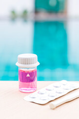 Sticker - Pool water in glass vials with pH table reagents and stirring rod on swimming pool edge, water analysis tools, free chlorine test