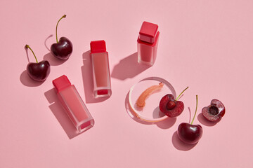 Scene for branding products. Red ripe cherries with lipsticks unbranded arranged on pink background. Cherries contain vitamin C and vitamin B, which help keep lips supple and safe for health