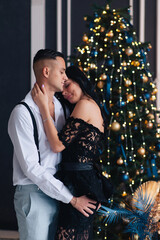 Poster - Portrait of a young couple in their living room at christmas eve.
Lovely couple in love embracing near christmas tree