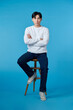 © makistock - handsome young man sitting on the chair, isolated on blue background