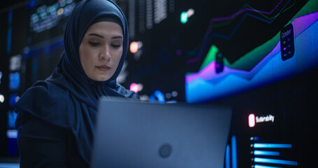 Leinwandbilder - Portrait of Arab Female Working in an Advanced Technology Company. Woman Wearing a Hijab, Using Laptop Computer in a Room with Statistics and Charts Settings on a Digital Screen