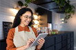 © Liubomir - Female barista waitress inside cafe using tablet, latin american restaurant owner smiling using tablet app to confirm online order.
