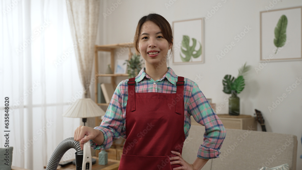 focus front face of happy young asian woman in apron with vacuum ...