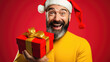 © MP Studio - Happy smiling man holding gift box on a colored background