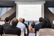 © kasto - Business and entrepreneurship symposium. Female speaker giving a talk at business meeting. Audience in conference hall. Rear view of unrecognized participant in audience.