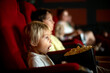 © Tomsickova - Cute child, boy, watching movie in a cinema, eating popcorn and enjoying