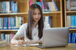 © EduLife Photos - Portrait of an Asian girl college student studying in library doing project assignment and preparing for examination