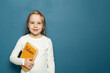 © millaf - Child student girl with Italian language book on the background of blue chalkboard