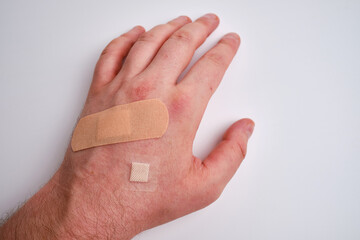 male hand with a medical adhesive plaster close-up. adhesive plaster on damaged skin. first aid for 