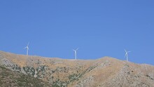Wind Turbines Moved By The Wind On A Hill With A Blue Sky In The Background.