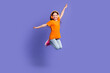 © deagreez - Full length photo of cheerful schoolkid dressed orange t-shirt flying in headphones arms wings isolated on purple color background