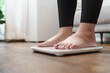 © Charlie's - Fat diet and scale feet standing on electronic scales for weight control. Measurement instrument in kilogram for a diet control.