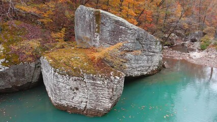 Wall Mural - Panning aerial rotation of large boulder and turquoise pool of water in Arkansas ozark mountain creek in autumn 