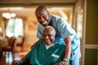 Young male caregiver pushing a senior man in his wheelchair in a nursing home smiling and laughing