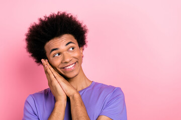 Photo of positive glad man wear trendy purple clothes two arms touch cheek interested look up empty space isolated on pink color background