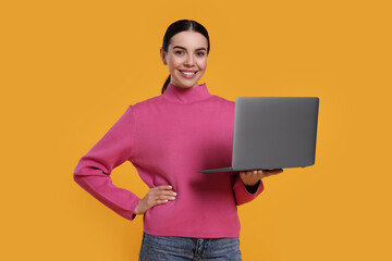 Wall Mural - Happy woman with laptop on orange background