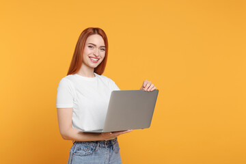 Wall Mural - Smiling young woman with laptop on yellow background, space for text