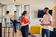 © .shock - Young business colleagues, including an African American businessman, engage in a conversation about business issues in the hallway of a modern startup coworking center, exemplifying dynamic problem