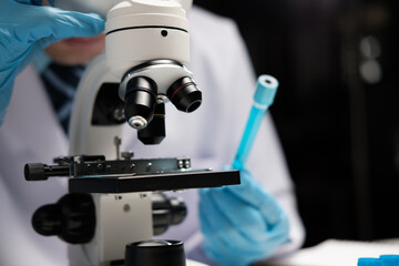 Wall Mural - male medical scientist examining specimen using microscope in modern laboratory.