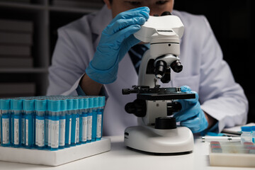 Wall Mural - male medical scientist examining specimen using microscope in modern laboratory.