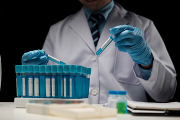 Wall Mural - Scientist hand taking a sample tube from a rack with machines of analysis in the lab background, Technician holding tube test in the research laboratory.