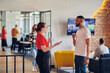 © .shock - Young business colleagues, including an African American businessman, engage in a conversation about business issues in the hallway of a modern startup coworking center, exemplifying dynamic problem