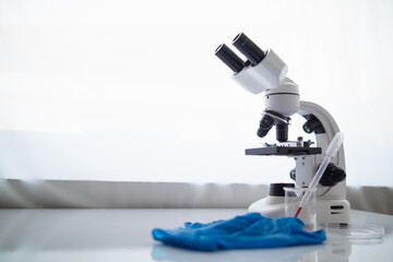 medical gloves and microscope are placed ontable in lab to prepare virologists who want to use lab to examine samples of virus they received from epidemic. Medical equipment for use in laboratorie