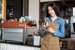 © yuttapon - Asian girl, small business owner, happy, sales of the month via tablet, success in coffee shopProud of yourself, confident, taking care of your family.Expand business, customers trust in the service