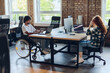 © .shock - Business colleagues work within a modern startup coworking office, with one of them, an African America in a wheelchair, actively engaging with computers and laptops to collaboratively address various