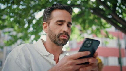 Hispanic businessman texting mobile phone message at city cafe terrace close up