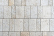 texture of a tiled beige stone wall as background, natural stone wall texture as background. Close-up of a wall clad in limestone