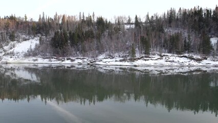 Poster - Aerial video of a frozen river with trees on the shore in winter