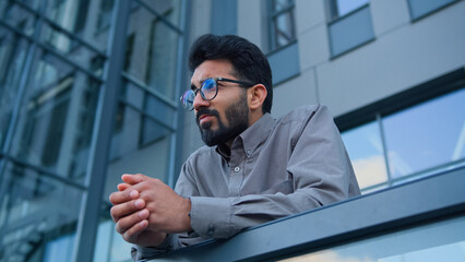 Sad thoughtful man Indian Arabian pensive businessman entrepreneur employer on terrace balcony outdoors depressed upset male worker in city concerned with business failure difficult decision crisis