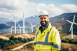 © Anna - Portrait of a smiling male engineer in a white helmet and reflective jacket standing on a wind turbine farm