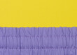 Fragment of purple fabric with an elastic band on a yellow background