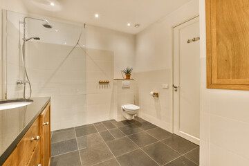 a modern bathroom with black tile flooring and wooden cabinetd cabinets in the corners on the left side