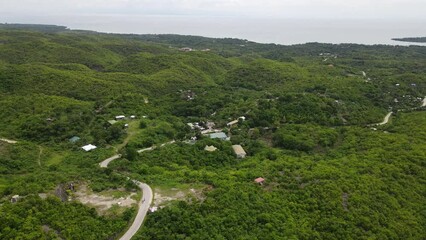 Canvas Print - Drone scenery of curly road in green terrain landscape with sea in the background