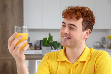 Sticker - Young man with glass of orange juice in kitchen, closeup