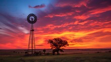 Colorful sunset with windmill and trees in rural Kansas north of Hutchinson. silhouette concept