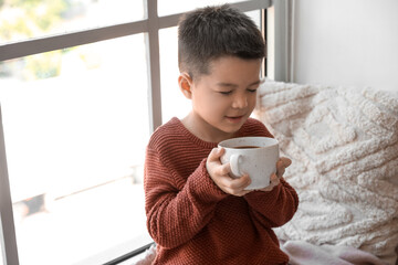 Poster - Cute little boy in knitted sweater with cup of cocoa at home