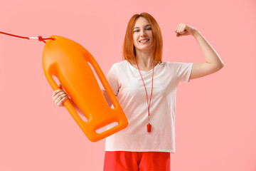 Wall Mural - Female lifeguard with rescue buoy showing muscles on pink background