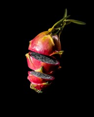 Poster - Ripe, pink and white dragonfruit cut into halves on a black background.