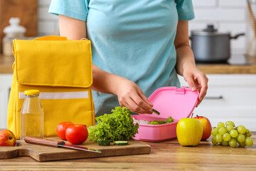 Wall Mural - Woman packing fresh meal into lunch box in kitchen