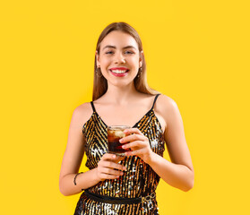 Wall Mural - Beautiful happy young woman with glass of tasty cola on yellow background