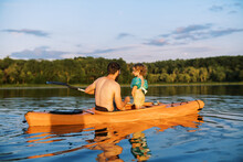 Father And Toddler Daughter Inside Kayak At Sunset On A Lake