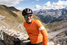 Cyclist Sits At The Top Of Famous Stelvio Pass In The Italian Alps.