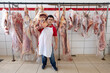 © Luciano Spinelli/Stocksy - Butcher standing in front of hanging cow carcass at his butchery